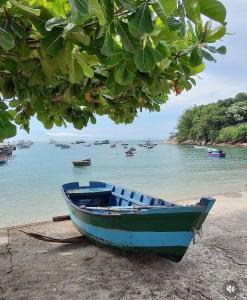 a blue boat sitting on the shore of a beach at Pousada Casa do Oscar in Governador Celso Ramos