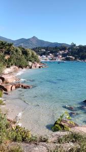 een strand met blauw water en een stad op de achtergrond bij Pousada Casa do Oscar in Governador Celso Ramos