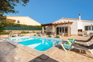 a swimming pool with chairs and a house at Villa Ingrid Porter by Villa Plus in Cala en Porter