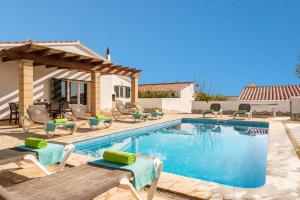 a swimming pool with chairs and a house at Villa Ingrid Porter by Villa Plus in Cala en Porter