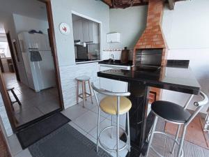 a kitchen with a counter and stools in a room at Casa de temporada Guarapari Casa Dule in Guarapari