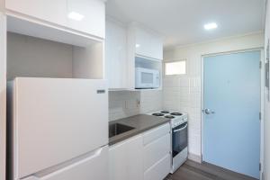 a white kitchen with a stove and a refrigerator at Blue Haven Holiday Apartments in Christ Church