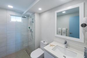 ein weißes Bad mit einer Dusche und einem Waschbecken in der Unterkunft Blue Haven Apartments in Christchurch
