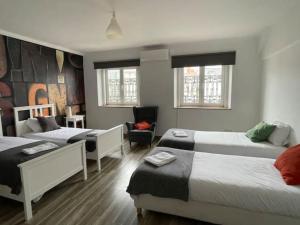 Cette chambre comprend 3 lits et une chaise. dans l'établissement Santos Deluxe Apartment, à Lisbonne