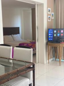 uma sala de estar com uma mesa de vidro e uma televisão em Beach Class Muro Alto Condomínio Resort - New Time em Porto de Galinhas
