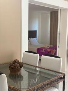 un soggiorno con tavolo in vetro e 2 sedie di Beach Class Muro Alto Condomínio Resort - New Time a Porto De Galinhas