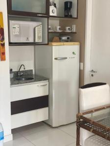 una piccola cucina con frigorifero e forno a microonde di Beach Class Muro Alto Condomínio Resort - New Time a Porto De Galinhas
