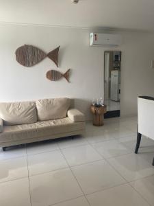 uma sala de estar com um sofá e dois peixes na parede em Beach Class Muro Alto Condomínio Resort - New Time em Porto de Galinhas
