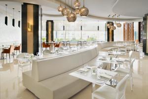 een restaurant met witte tafels, stoelen en ramen bij Crowne Plaza Hotel Riyadh Minhal, an IHG Hotel in Riyad