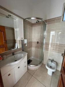 y baño con ducha, lavabo y aseo. en Villa Multifamiliare a 300mt dal Mare, en Baia Domizia