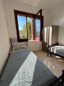 1 dormitorio con 2 camas y ventana en Villa Multifamiliare a 300mt dal Mare, en Baia Domizia