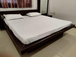 Bett mit weißer Bettwäsche und Kissen in einem Zimmer in der Unterkunft Just homes 2 bhk Service appt in Pune