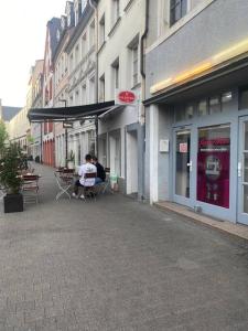 two people sitting at tables outside of a building at Schöne und Gemütliche Wohnung in Trier Zentrum in Trier