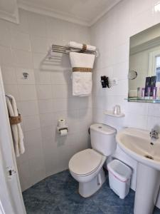 a white bathroom with a toilet and a sink at Hostal Fidalgo in Oviedo