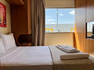 1 dormitorio con 1 cama y ventana grande en Multiparque Hplus Long Stay en Brasilia