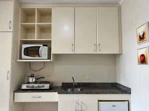 a kitchen with white cabinets and a microwave at Multiparque Hplus Long Stay in Brasília
