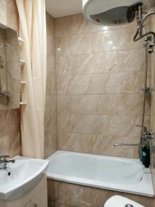y baño con bañera blanca y lavamanos. en Apartamenti Miera Osta en Liepāja