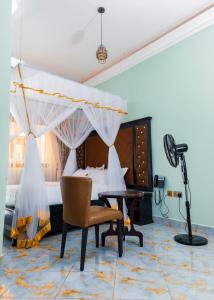 ein Schlafzimmer mit einem Bett, einem Schreibtisch und einem Stuhl in der Unterkunft Romeos Hotel in Kampala