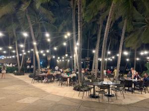 a group of people sitting at tables under palm trees at night at Blue Beach Apartments in Aquiraz