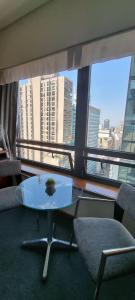 a glass table and chairs in a room with a large window at Dg Apart Obelisco in Buenos Aires