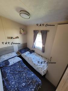 two beds in a room with a window at K & K Caravan Southview in Skegness