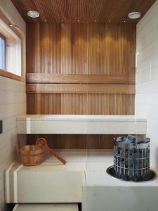 a sauna with a wooden wall and a bucket at Levin Primus in Levi
