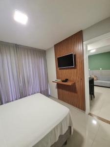 Habitación de hotel con cama y TV en Residencial Bombinhas, en Bombinhas