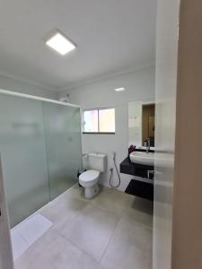 a white bathroom with a toilet and a sink at Residencial Bombinhas in Bombinhas