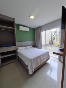 1 dormitorio con cama y pared verde en Residencial Bombinhas, en Bombinhas