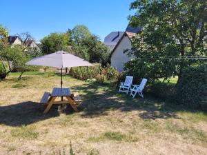 einen Picknicktisch mit einem Sonnenschirm und 2 Stühlen in der Unterkunft AU GRE DES SAISONS in Thannenkirch