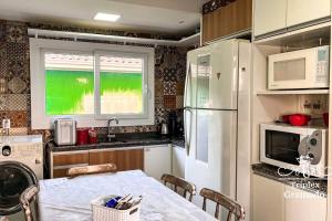 uma cozinha com uma mesa e um frigorífico branco em Casa Triplex com 03 Suítes, Cond no Centro Gramado em Gramado
