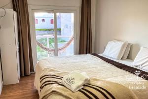 um quarto com uma cama e uma porta de vidro deslizante em Casa Triplex com 03 Suítes, Cond no Centro Gramado em Gramado