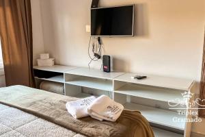 um quarto com uma cama e uma televisão na parede em Casa Triplex com 03 Suítes, Cond no Centro Gramado em Gramado
