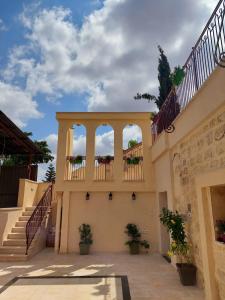 - un bâtiment avec 2 balcons et des escaliers avec des plantes en pot dans l'établissement Reeja art gallery, à Nazareth