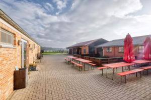 une rangée de tables et de bancs avec parapluies rouges dans l'établissement Hoeve Megusta, à Vlimmeren