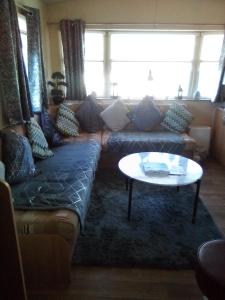 Deluxe 3 bedroom Lyons Robin hood oaklands with free wifi free sky في Meliden: غرفة معيشة مع أريكة وطاولة
