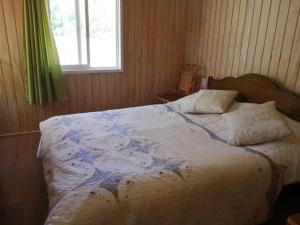 a bedroom with a bed and a window at Cabaña May Pao, para 3 en Melipeuco cerca del Parque Nacional Conguillio in Melipeuco
