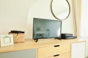 - une télévision assise au-dessus d'une commode avec un miroir dans l'établissement Appartement de l'Hippodrome avec deux chambres, à Deauville