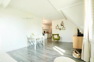 een witte woonkamer met een tafel en stoelen bij Appartement de l'Hippodrome avec deux chambres in Deauville
