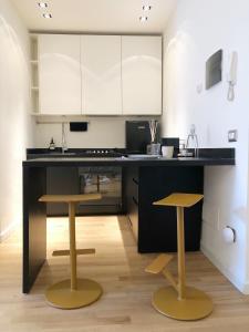 een keuken met een zwart aanrecht en 2 krukken bij City Center Apartment Piacenza in Piacenza