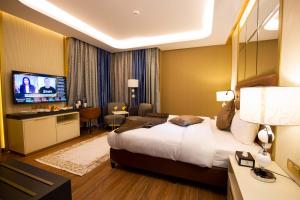 um quarto de hotel com uma cama grande e uma televisão em Petra Moon Luxury Hotel em Wadi Musa