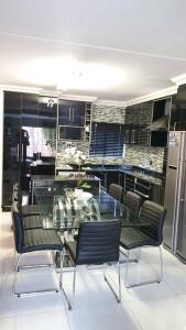 comedor con mesa de cristal y sillas en Upmarket 3 Bedroom Apartment, en Johannesburgo