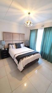 a bedroom with a large bed with blue curtains and a chandelier at Upmarket 3 Bedroom Apartment in Johannesburg