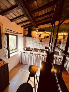a kitchen with a stove and a sink and a stool at La Casa sui Tetti -Calcata in Calcata