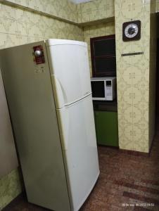 um frigorífico branco numa cozinha ao lado de um micro-ondas em Dpto céntrico con estacionamiento em San Miguel de Tucumán