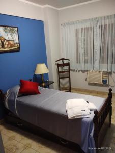 um quarto com uma cama grande e uma almofada vermelha em Dpto céntrico con estacionamiento em San Miguel de Tucumán