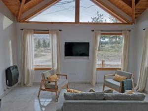 uma sala de estar com um sofá e cadeiras e uma televisão em Los Robles Patagonia em Esquel