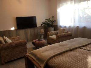 - une chambre avec un lit, des chaises et une télévision à écran plat dans l'établissement FeWo Khuki, à Leipzig
