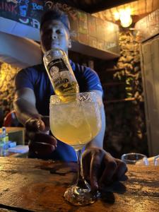 Un uomo seduto al bar con un bicchiere di birra di Rosario EcoHotel a Isla Grande