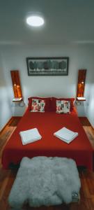 a bedroom with a red bed with two towels on it at Xalpen B&B in Puerto Natales